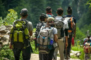 Group of hikers with backpacks walking along a trail in forest area